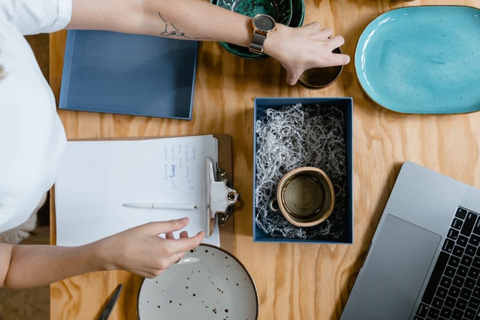 Small business owner packing a ceramic mug into a shipping box at a workbench