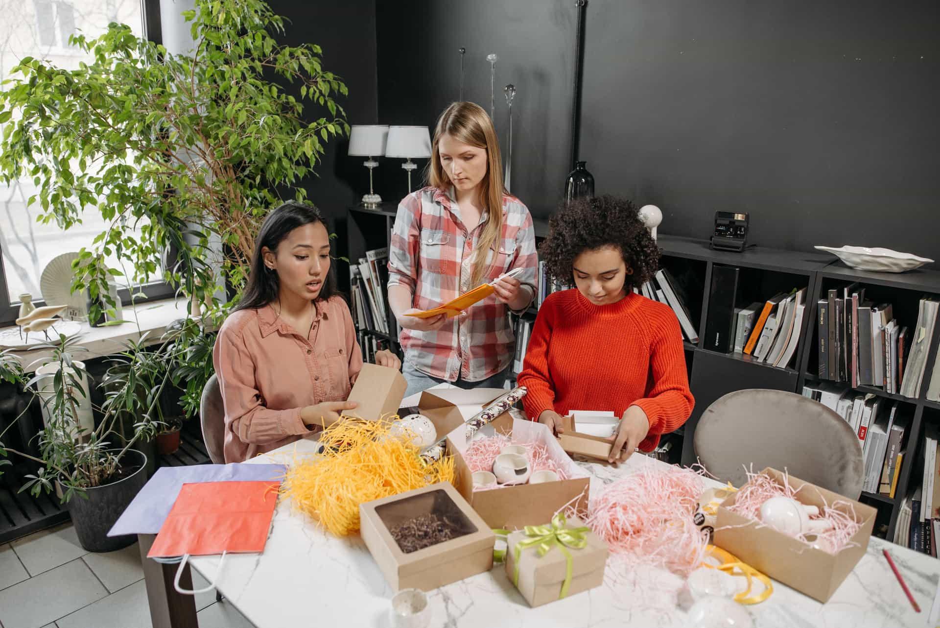 Small business team packing orders at a workspace surrounded by boxes