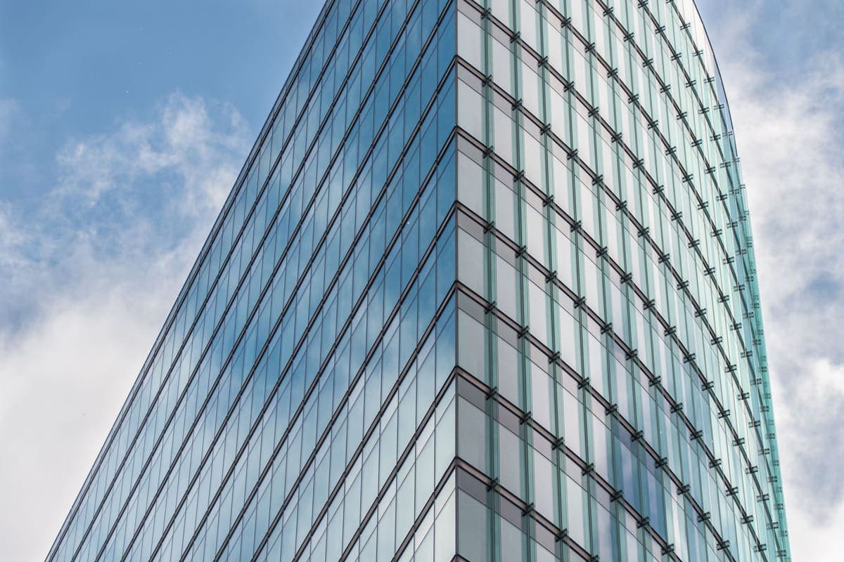Sleek glass office skyscraper reflecting blue sky and clouds