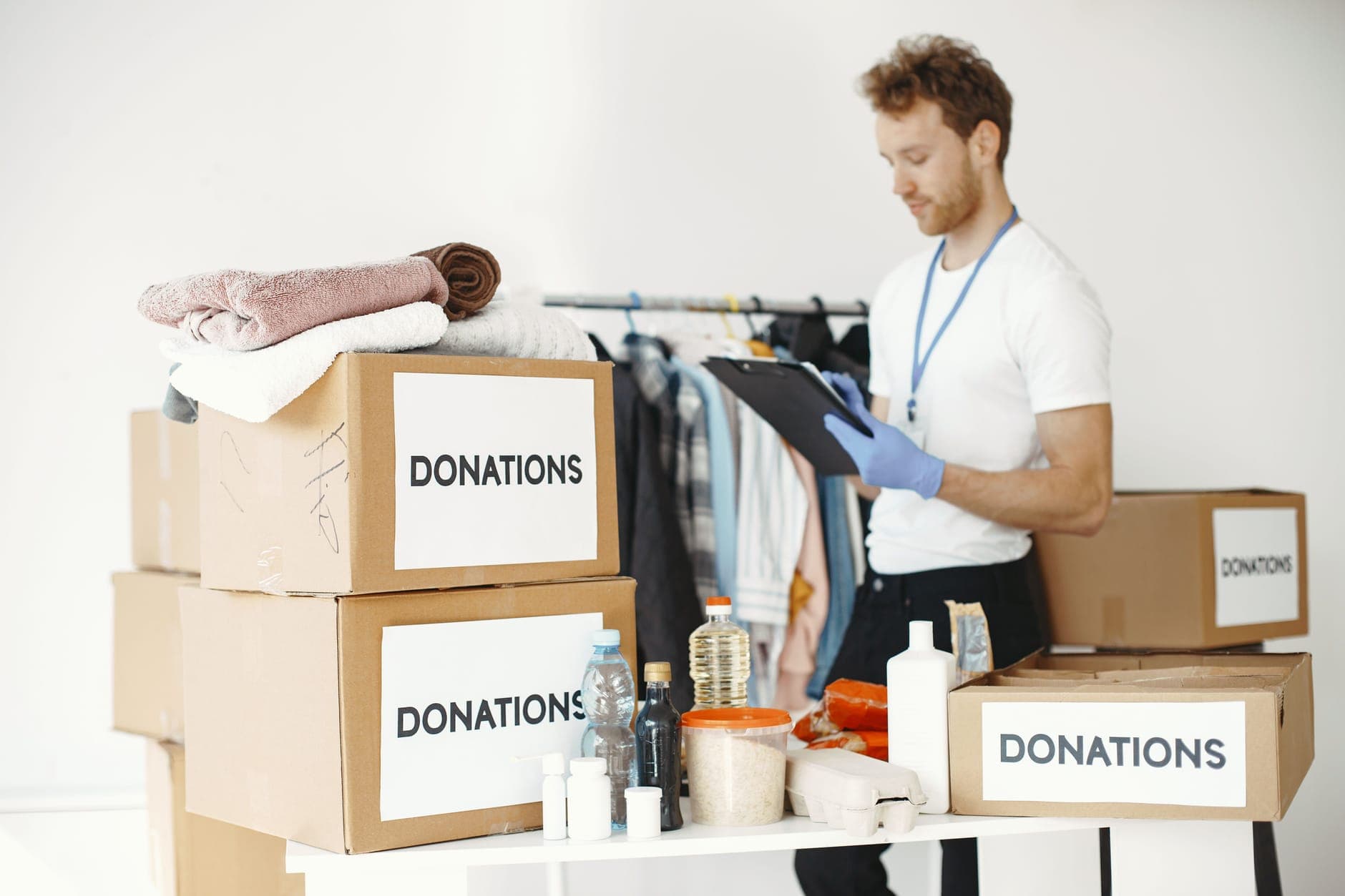 Volunteer sorting donated goods into boxes on a table at a community center