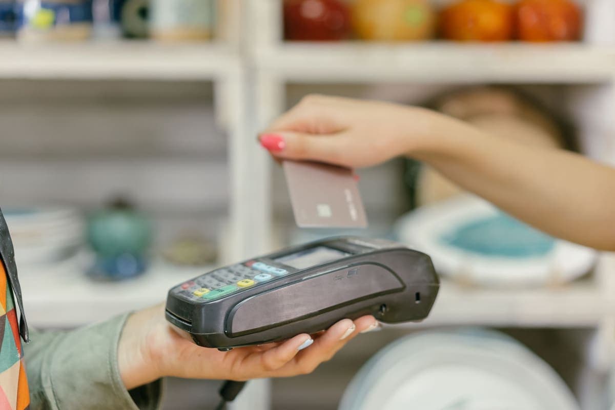Hand tapping a credit card on a point-of-sale payment terminal