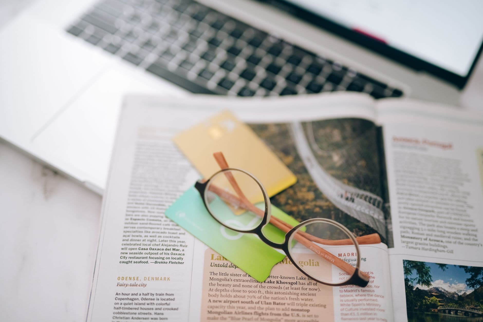 Payment cards and reading glasses on a desk beside a laptop