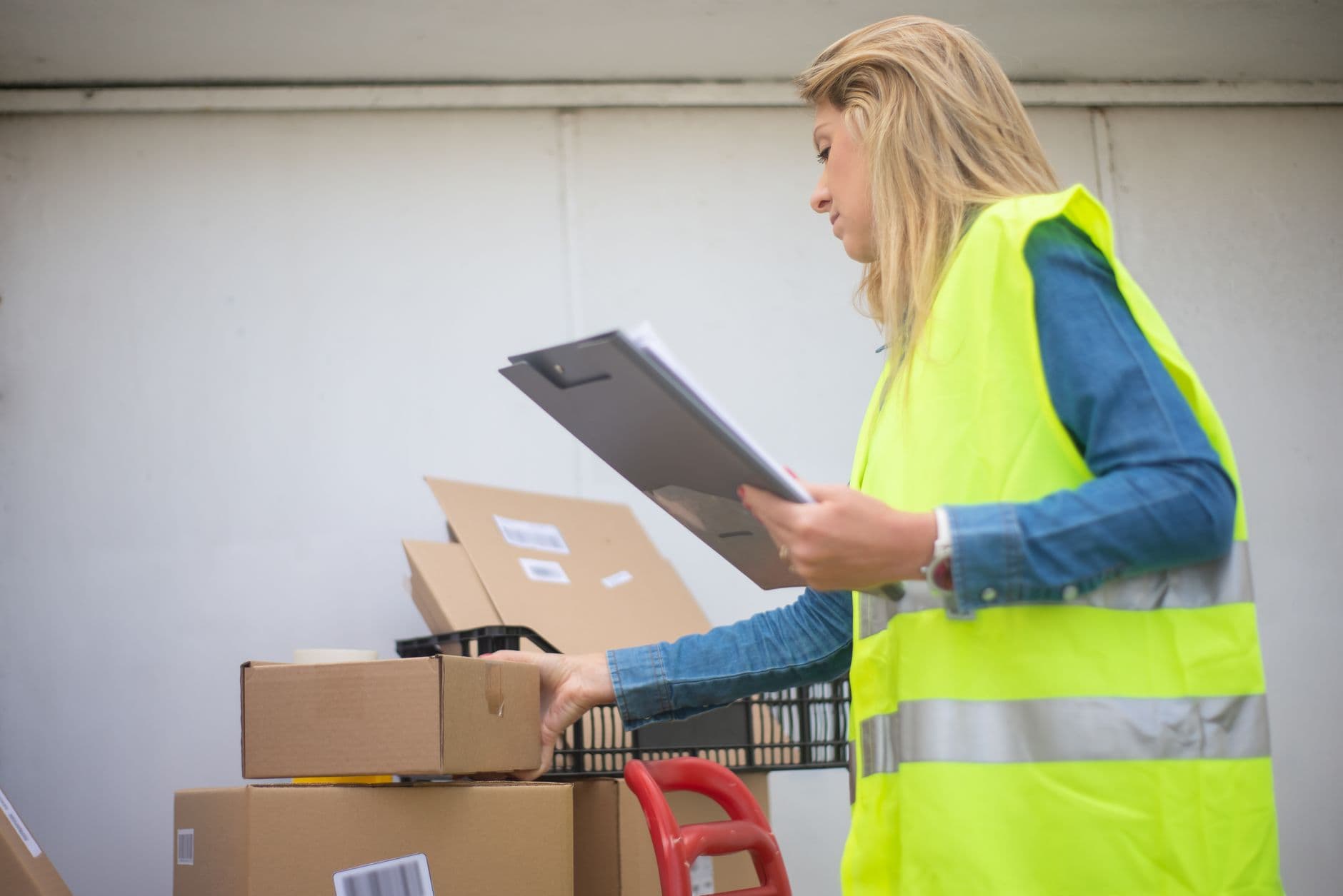 Warehouse worker in a high-visibility vest checking delivery boxes