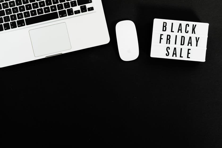 Black Friday sale sign beside a laptop and mouse on a dark desk