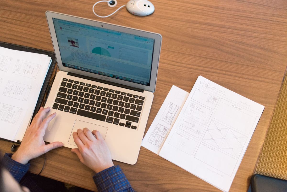 Hands typing on a laptop keyboard with business paperwork alongside