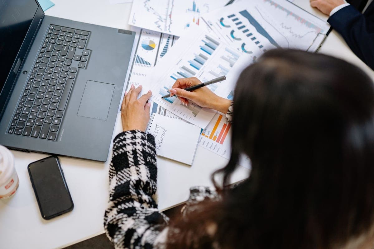 Business documents and a pen laid out on a desk beside a laptop